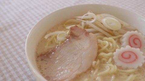Serving the topping Naruto fish cake on pork bone thick soup noodles for Japanese food image