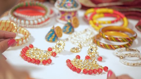 A young Indian bride wearing a beautiful earrings while getting ready. Fashionable jewelry collection displayed for sale on the counter of a jewelry store - glamor, luxury, lifestyle, makeup