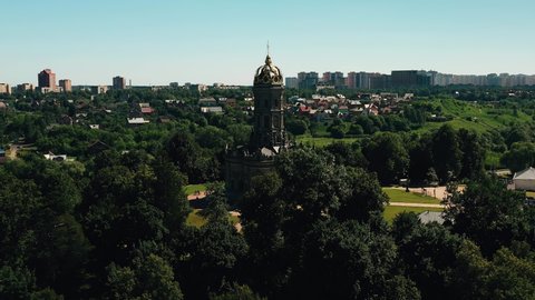 Among the trees, against the background of the sky and the city, a high christian cathedral is visible in the distance. The cathedral is made in the form of a tower