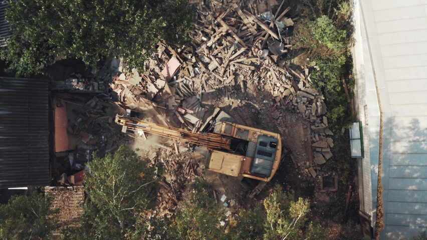 Demolition of building aerial top view from above. Destruction of old house, excavator on rubble