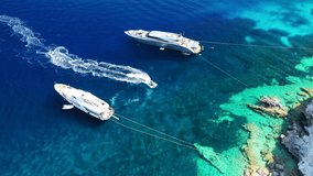 Aerial drone video of luxury yachts anchored in paradise beach of Psarou, island of Mykonos, Cyclades, Greece