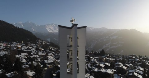 Aerial shot of a church at dawn in a beautiful Swiss village covered in snow