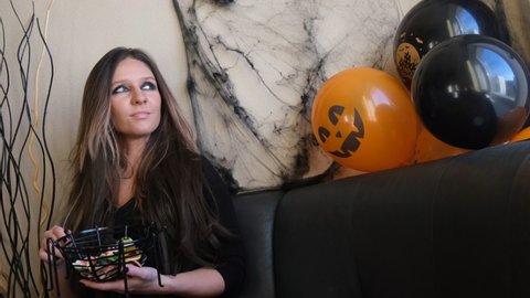 A young woman at a Halloween themed house party eats scary sweets.