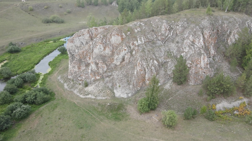flying around a cliff, on a green field