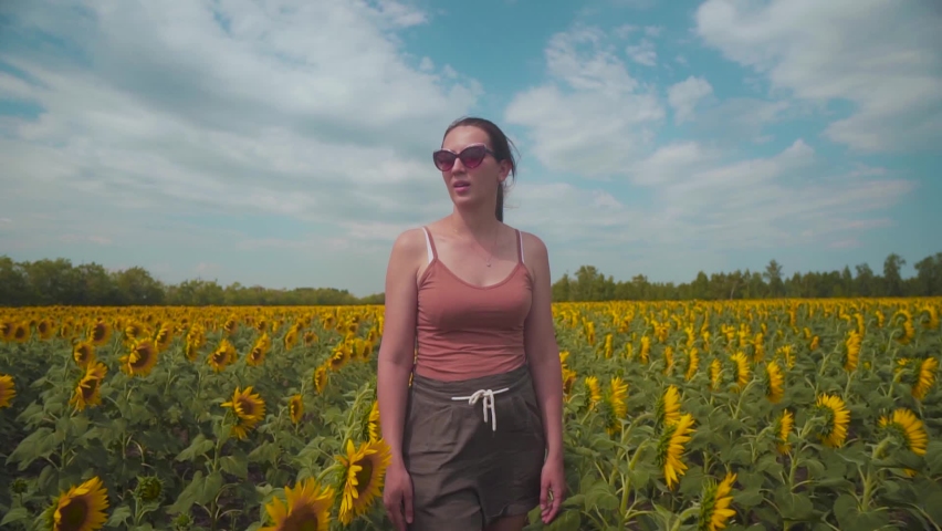 Woman Walking in an Agricultural Field with Yellow Sunflowers and Touching Flowers Experiencing a Feeling of Freedom. The Farmer Inspects His Land. Agriculture industry