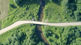 Aerial view of rural wooden bridge over small forest river. Top down drone view of little river. Countryside. Rotating top down. B roll footage 4k.