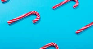 Animation of christmas joy text over christmas candy canes on blue background. christmas, tradition and celebration concept digitally generated video.