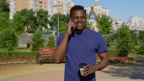 Portrait smiling African American man talking on mobile phone holding paper cup for coffee or tea in summer. Happy adult male uses smartphone communicates with best friend in park - Powered by Shutterstock - Get 15% off with code: PIKWIZARD15