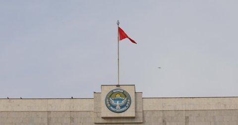 Bishkek, Kyrgyzstan - October 21, 2021:  National emblem and flag of Kyrgyzstan on the building of The White House