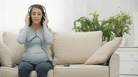 4k slowmotion video of pregnant woman listening to music.
