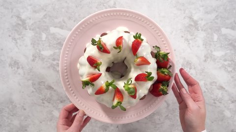 Time lapse. Flat lay. Step by step. Decorating freshly baked red velvet bundt cake with organic strawberries.
