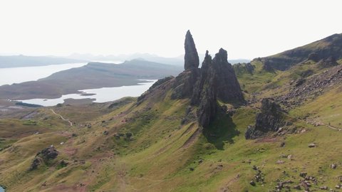 Panning Towards Old Man Of Storr Isle Of Skye With Lush Green Grass And Contrasting Cliff Faces On An Overcast Day
