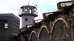 Prison watchtower with dilapidated brick arched wall in foreground. - Powered by Shutterstock - Get 15% off with code: PIKWIZARD15