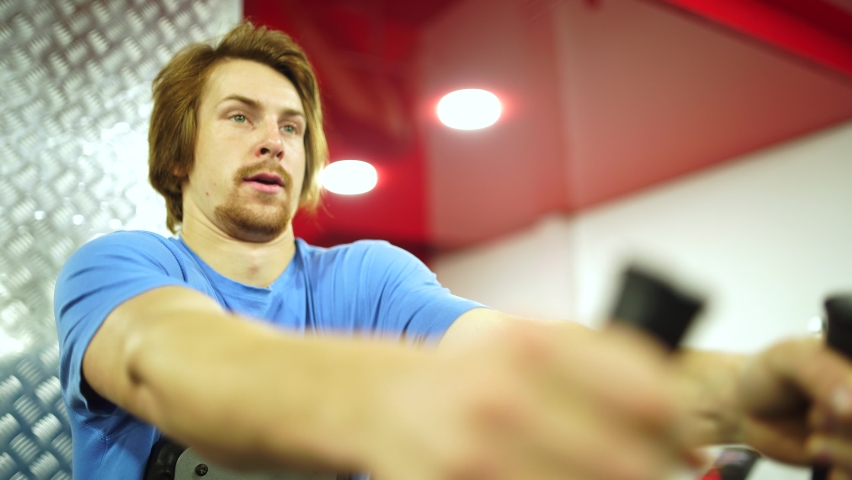 red-haired guy worked out the training apparatus in the red gym.close-up