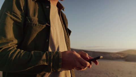 A young Caucasian male texting on the phone at the beach. Close up of man looking at the phone. High quality 4k footage 