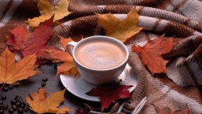 Autumn, fall leaves, hot cup of coffee and warm plaid on a wooden table background. Seasonal, morning coffee, sunday relaxing and still life concept. Camera movement in a circle