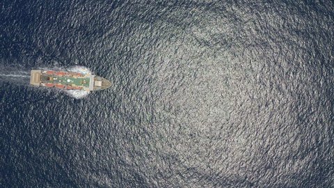 Aerial top view of cargo ship carrying container and running for export goods from cargo yard port to custom ocean concept freight shipping by ship. Large container ship at sea. Aerial top down.