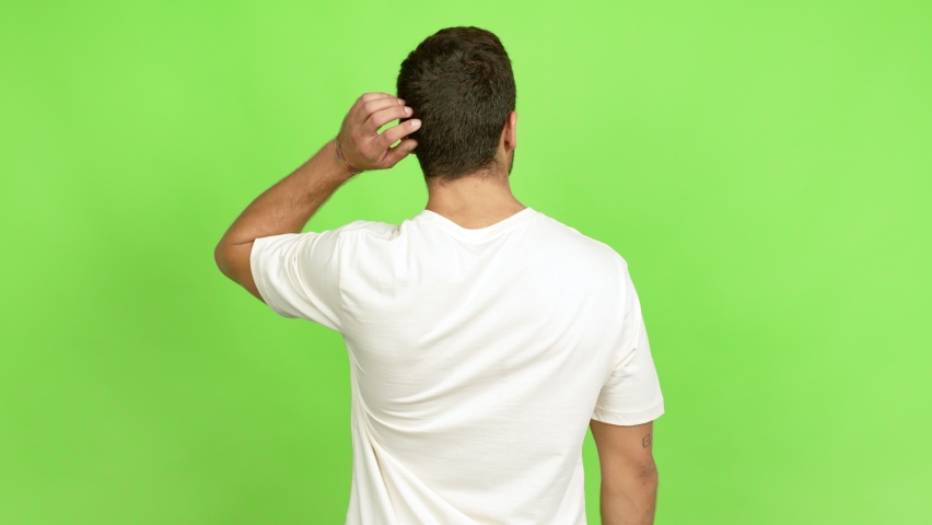 Handsome man on back position looking back while scratching head over isolated background