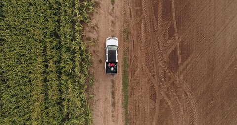 AERIAL Farmer driving his pickup truck, bringing a huge agriculture drone to a field early in the morning