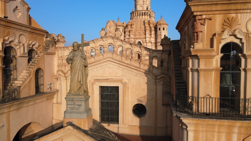 Aerial close up shot overlooking at statue of Christ on the cathedral roof, pull out reveals the whole church building exterior, at Cordoba, Argentina.