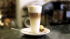 caffe latte finished and ready to be served with a foam on top and sweet on a side in restaurant environment slow motion