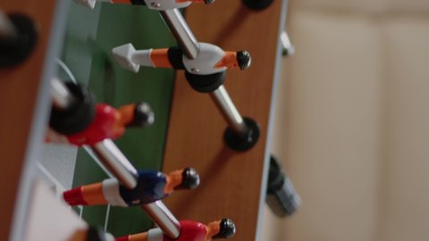 Vertical video: Close up of foosball game table to do fun activity and entertainment in office. Toy with football match and players to score goal, colleagues meeting after work with drinks. Soccer