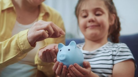 happy family piggy bank. mom and daughter a put coins in future the piggy bank. mortgage loan savings home in crisis coronavirus concept. happy family hoarding money in a piggy bank