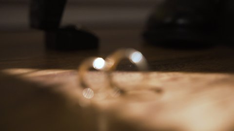 Two gold wedding rings on wooden table. Paired jewelry. Ray of light falls on wedding rings. Change of focus. Decoration symbolizes infinity, unity and love between people. Creating family.Wedding day
