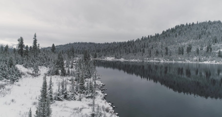 Stream and lake among snowy trees and hills in the mountains in winter. Alpine landscape. High quality 4k footage