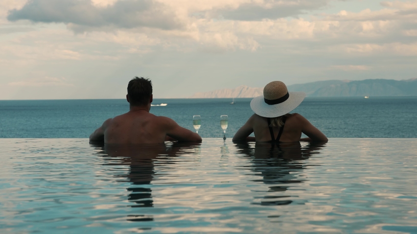 couple enjoying romantic view to the sea and drinking champagne in infinity pool at luxury resort. honeymoon vacation Royalty-Free Stock Footage #1081088393