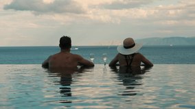 couple enjoying romantic view to the sea and drinking champagne in infinity pool at luxury resort. honeymoon vacation - Powered by Shutterstock - Get 15% off with code: PIKWIZARD15