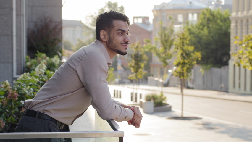 Side view portrait relaxed hispanic business man standing at railing modern skyscraper office building looking away on city street thinking resting. Close up successful guy male on balcony terrace | Shutterstock HD Video #1081089194