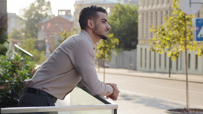 Side view portrait relaxed hispanic business man standing at railing modern skyscraper office building looking away on city street thinking resting. Close up successful guy male on balcony terrace | Shutterstock HD Video #1081089194