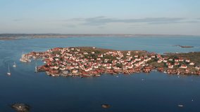 Swedish island with summer houses in typical colors. Evening sunset light over ocean archipelago. High overview aerial clip overlooking islands