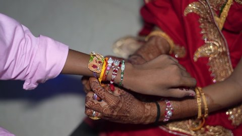 Indian sister tying rakhi, Raksha bandhan to brother's wrist during festival or ceremony.