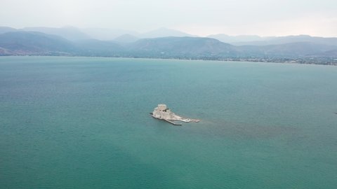 Panoramic shot of Bourtzi castle in the middle of water with mountains