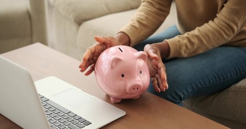 Woman inserting coins into piggy bank