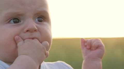 small child sucks his fingers on his hand, gums of small kid are itchy, baby teeth are teething, gums hurt, child first year of life, problem healthy mouth, licking and drooling fist, close-up face