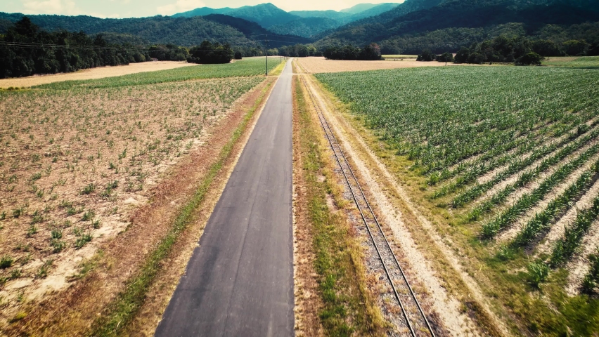 Rural Country Landscape of sugarcane farms with mountains in the background and a road and train railway tracks going between taken in Shannonvale Mossman near Port Douglas and the Daintree rainforest
