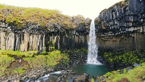 Amazing View of Basalt Black Waterfall with Blue Sky and Green Grass. Skaftafell