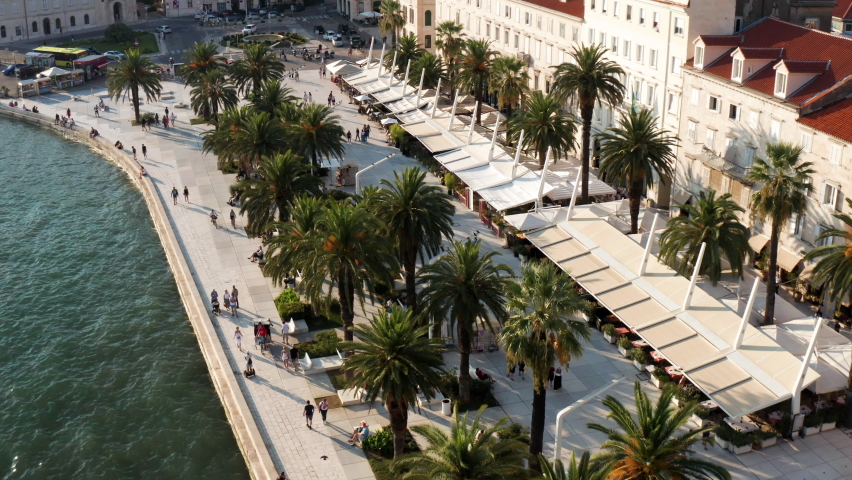 Popular Riva With Palm Trees And Restaurants Along Waterfront Buildings In Split, Croatia. - aerial Royalty-Free Stock Footage #1081123862