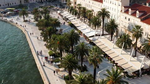 Popular Riva With Palm Trees And Restaurants Along Waterfront Buildings In Split, Croatia. - aerial