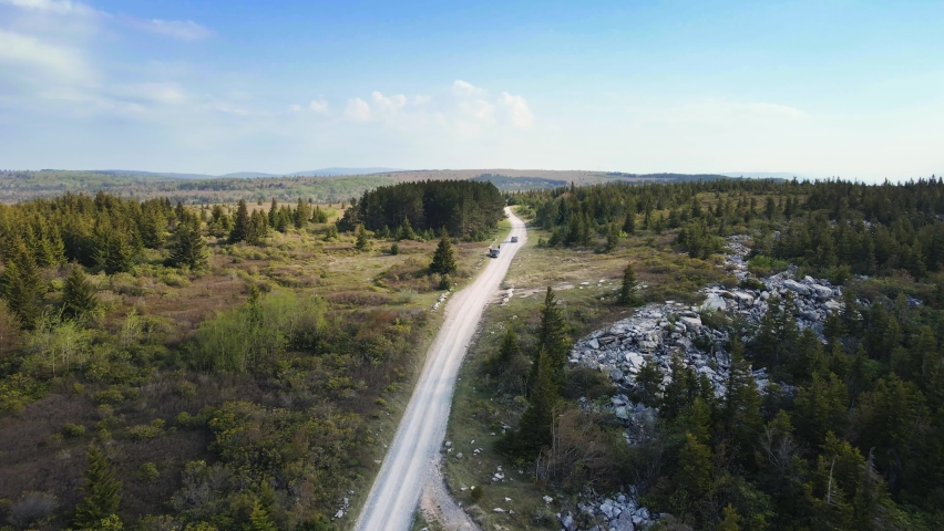 Aerial, single dirt road in middle of forest hill wilderness. Car driving in distance, Dolly Sods West Virginia