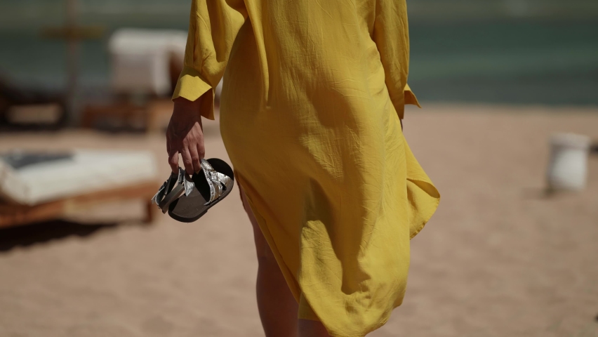 Woman in yellow dress is walking on sandy sea beach in summer vacation | Shutterstock HD Video #1081125134