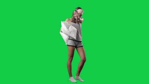 Tired sleepy young woman in pajamas with pillow showing stop gesture. Do not disturb. Full body isolated on green screen background