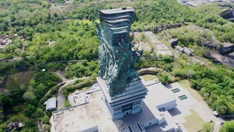 Aerial shot circling the Garuda Wisnu Kencana statue in Bali, Indonesia. Famous religious statue with residential neighborhoods in the background
