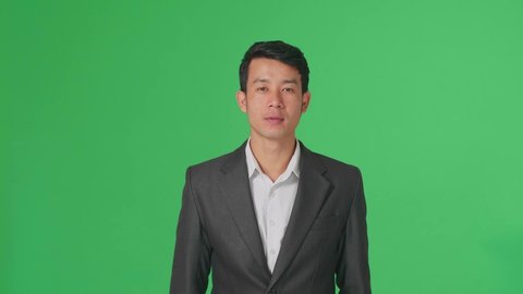 Happy Asian Business Man Showing Thumbs Up Gesture While Standing In The Green Screen Studio
