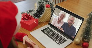 Caucasian woman having christmas video call on laptop with caucasian grandparents on screen. christmas, festivity and communication technology.