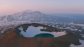 Aerial view of Gorely volcano, Kamchatka. Blue lake inside a crater on a snow-capped mountain top