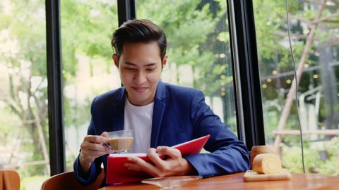 Asian businessman drinking hot coffee in Co-working space to take break from work. Happy relaxing in a coffee shop. Concept White collar	